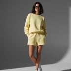 Woman wearing Anointed Garments yellow fleece lounge shorts and matching sweatshirt with drawstring waist and pockets
