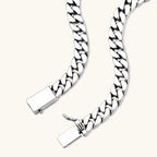 Polished 925 sterling silver Cuban link chain necklace, 550mm length, shown flat and draped on cream background.
